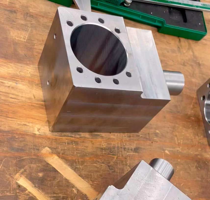 Un bloque de metal con un agujero en el medio se encuentra sobre una mesa de madera.