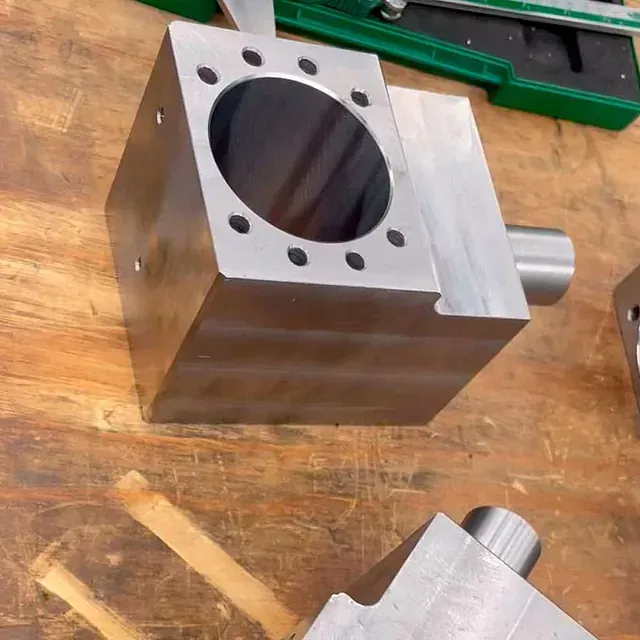 Un bloque de metal con agujeros está sobre una mesa de madera.