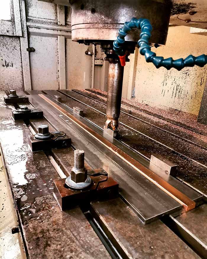 Una máquina con una manguera conectada a ella está cortando un trozo de metal.