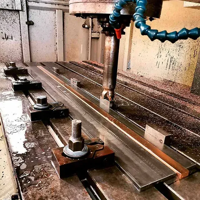 Una máquina con una manguera conectada está cortando un trozo de metal.