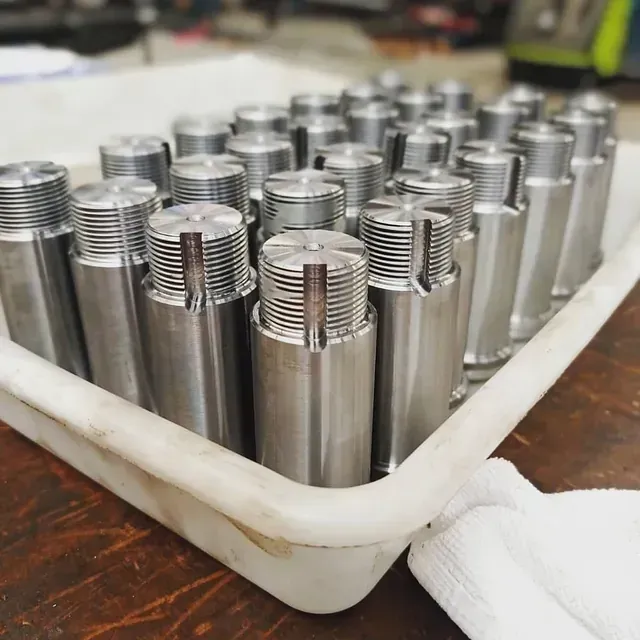 Una bandeja llena de muchos cilindros de metal sobre una mesa de madera.