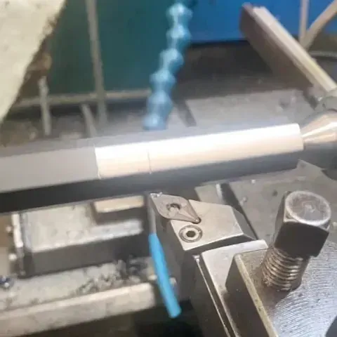 Una máquina está cortando un trozo de metal en un torno.