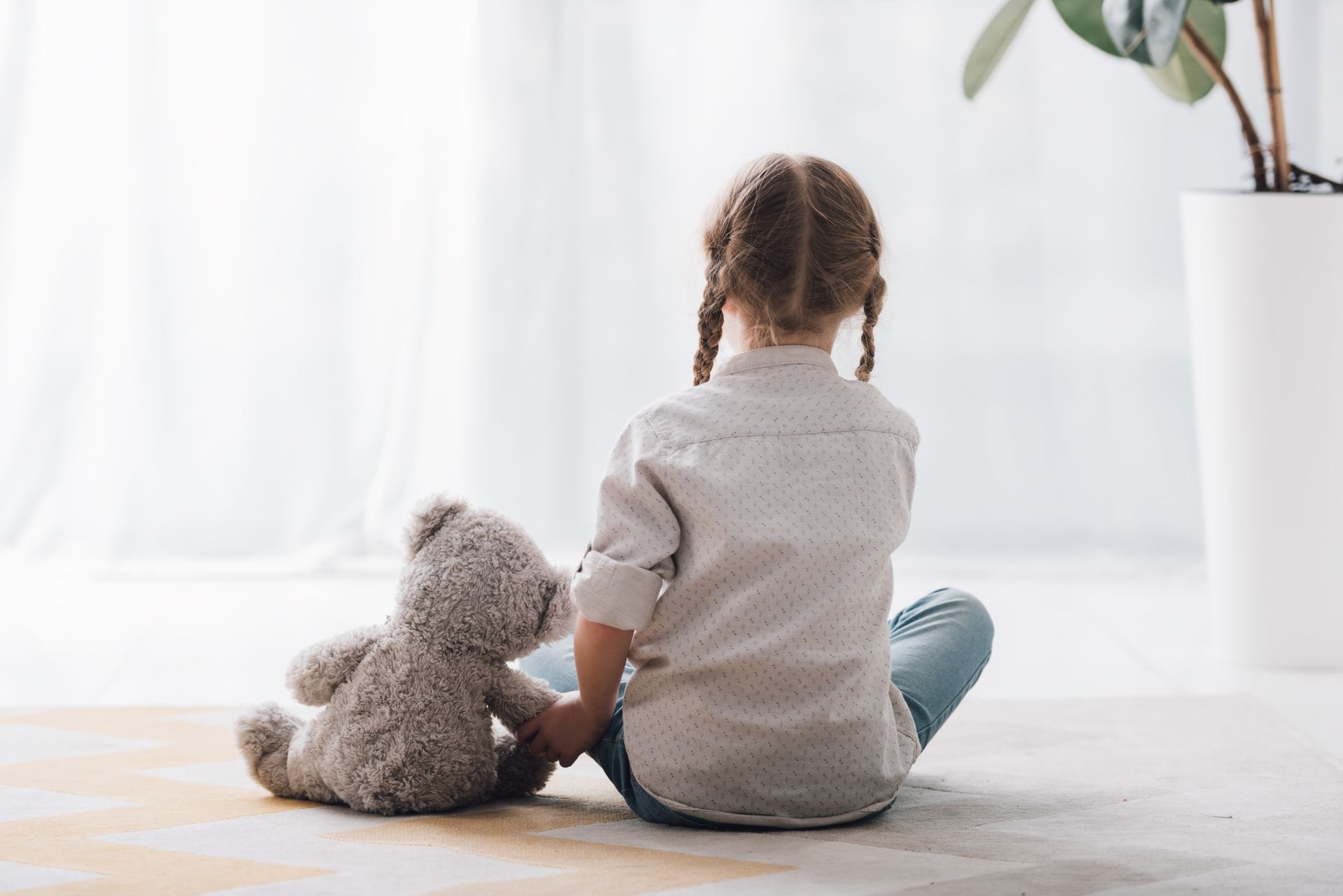 Un enfant de dos avec un ours en peluche