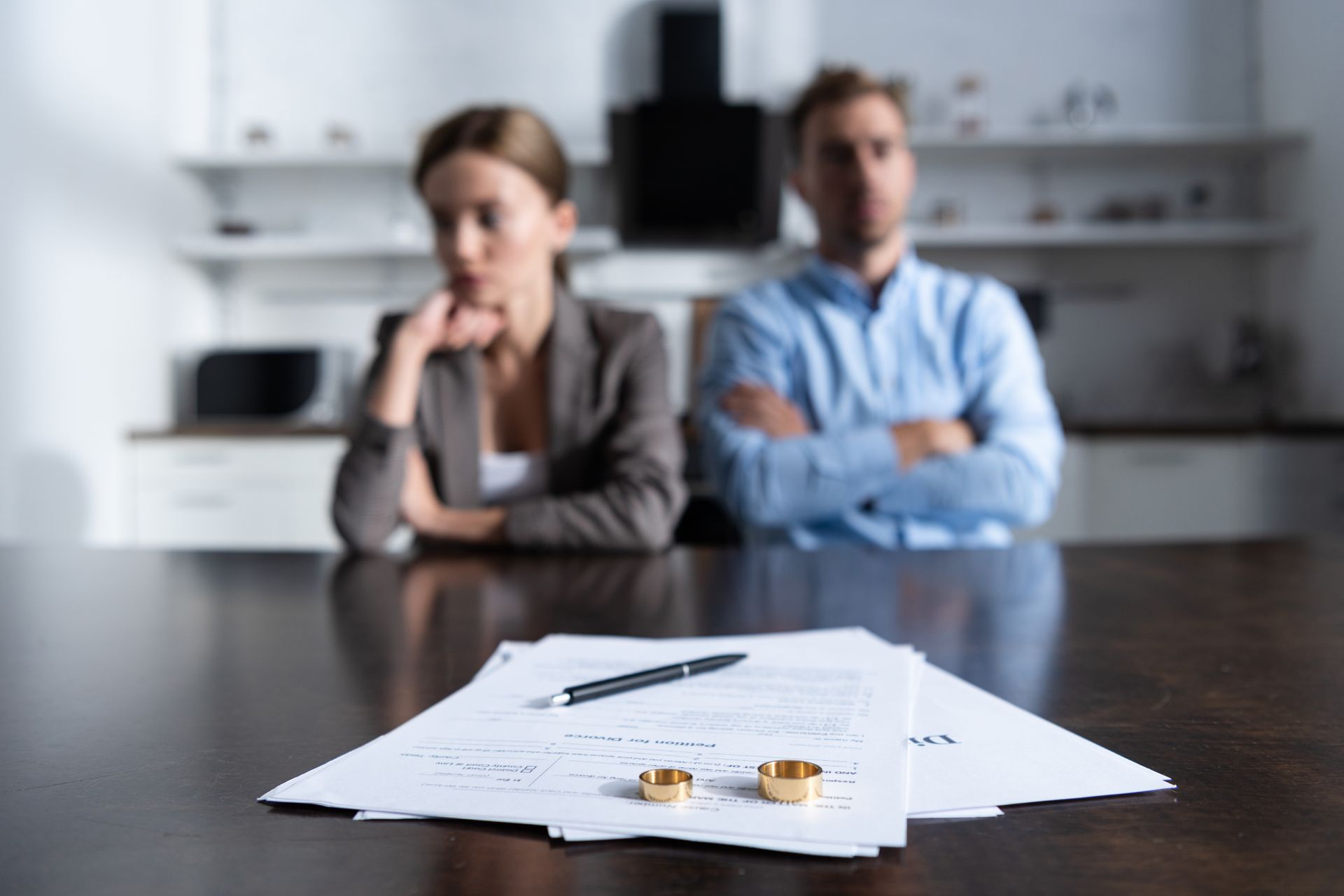 Gros plan sur des documents de divorce avec les alliances et un couple en arrière-plan