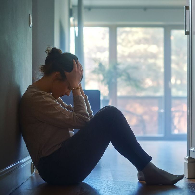 Une femme assise par terre dans un couloir