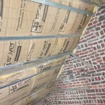 Un mur en pierre rouge et blanc en travaux d'isolation.