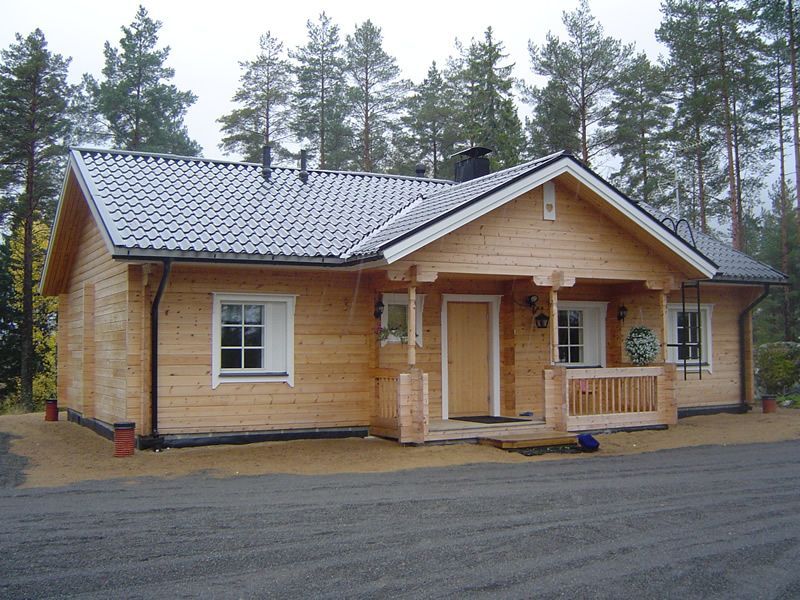 Pieni puinen mökki kuistilla, soratien varrella mäntymetsässä