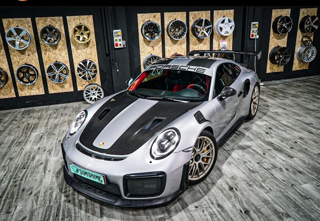 Un Porsche 911 GT2 RS plateado está aparcado en un garaje.