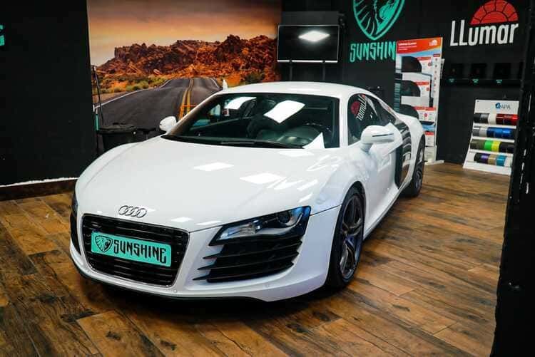 Un Audi R8 blanco está estacionado en una habitación con suelo de madera.