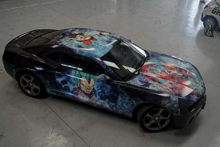 Un automóvil con una envoltura de Dragon Ball Z está estacionado en un garaje.