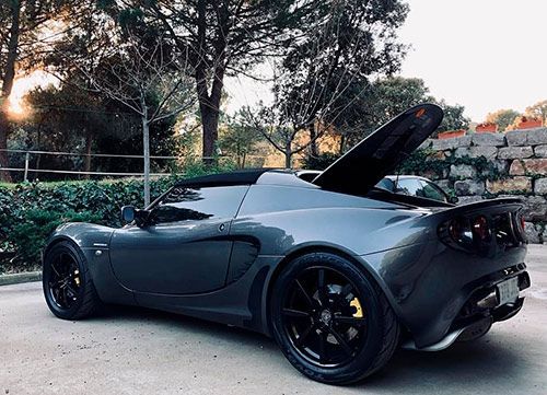 Un coche deportivo negro con el capó levantado está estacionado en un estacionamiento.