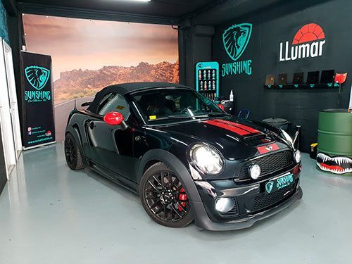 Un mini cooper negro está estacionado en un garaje.
