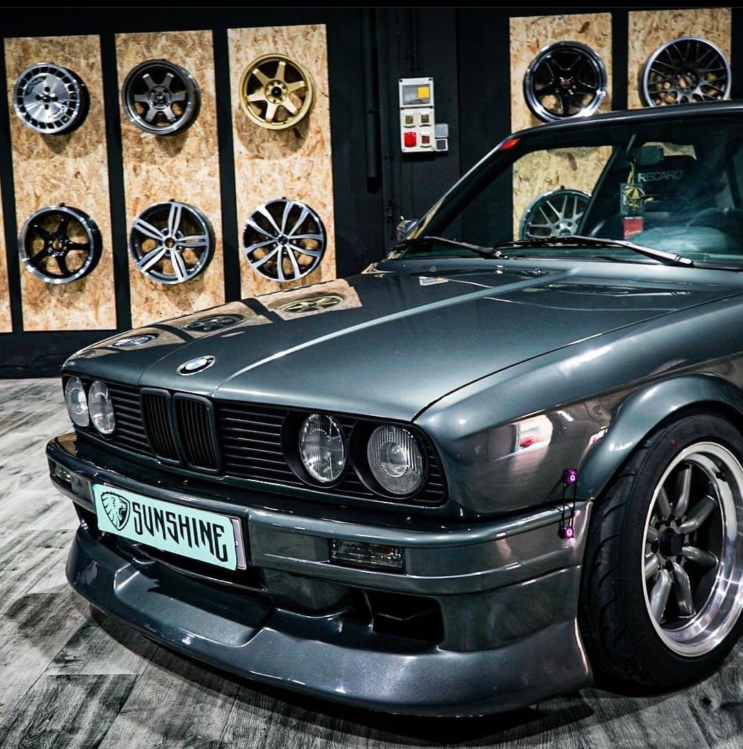 Un BMW está aparcado delante de un muro de ruedas.