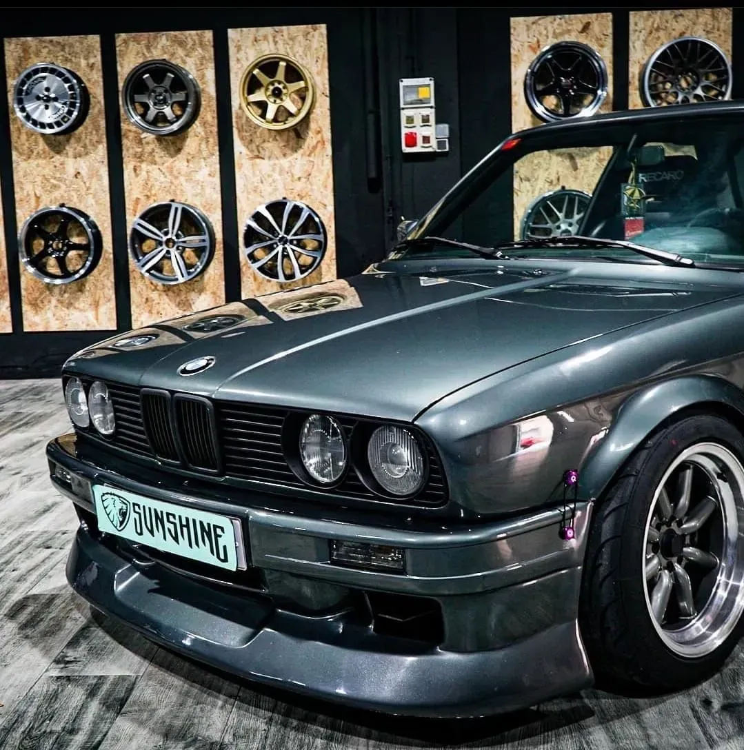 Un coche negro está aparcado delante de una pared de ruedas.