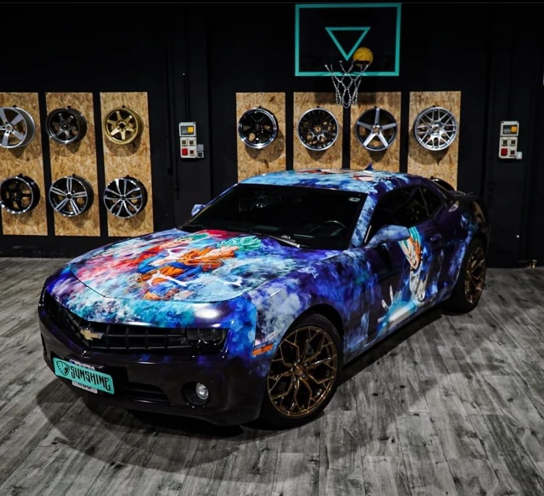 Un coche con un cuadro está aparcado delante de un aro de baloncesto.