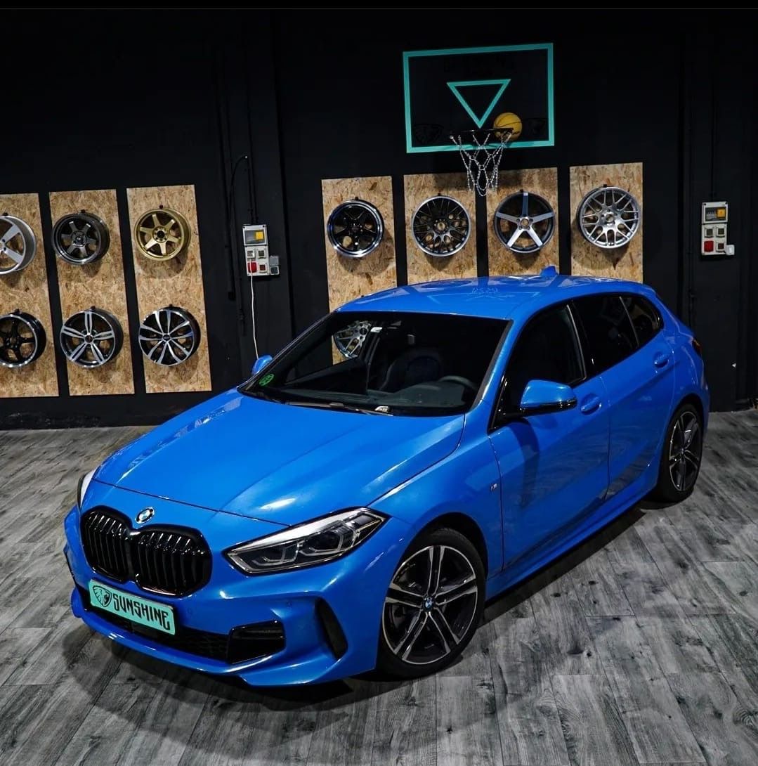 Un coche azul está aparcado delante de un aro de baloncesto.