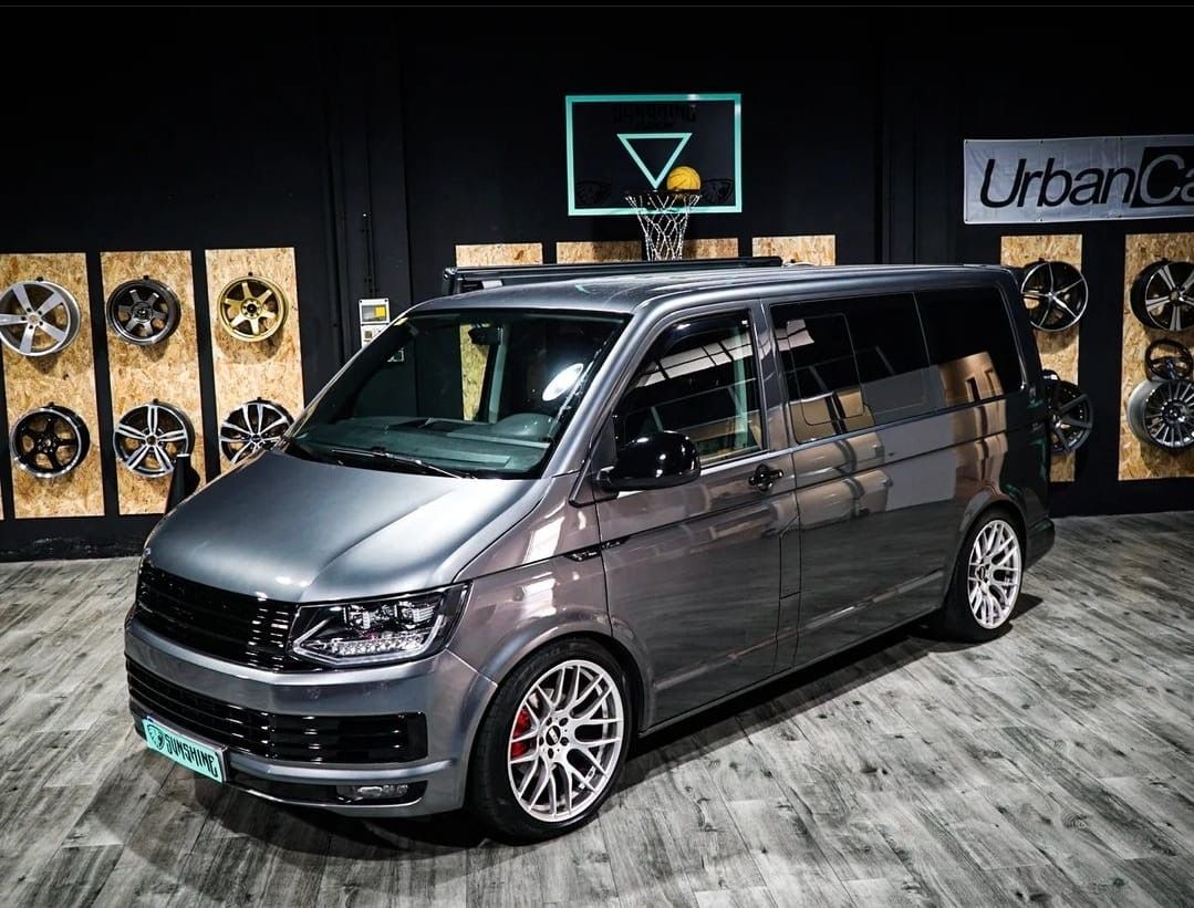 Una camioneta gris está estacionada frente a un aro de baloncesto.