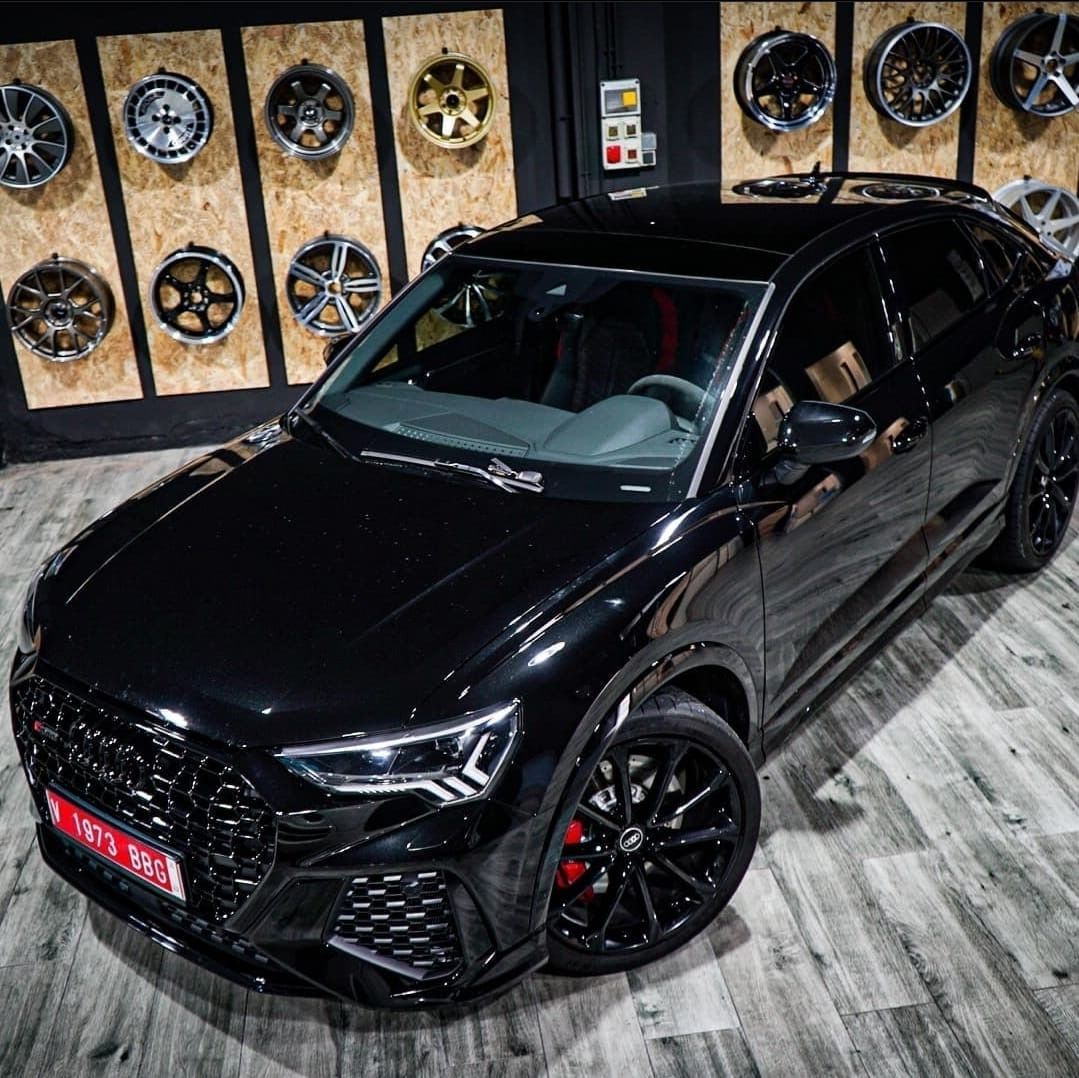 Un coche negro está aparcado delante de una pared de ruedas.