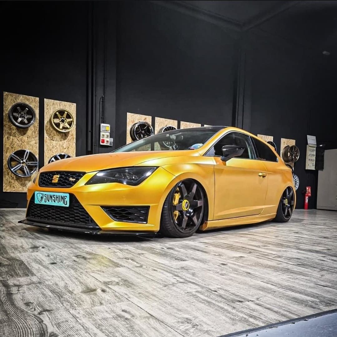 Un coche amarillo está aparcado sobre un suelo de madera en un garaje.