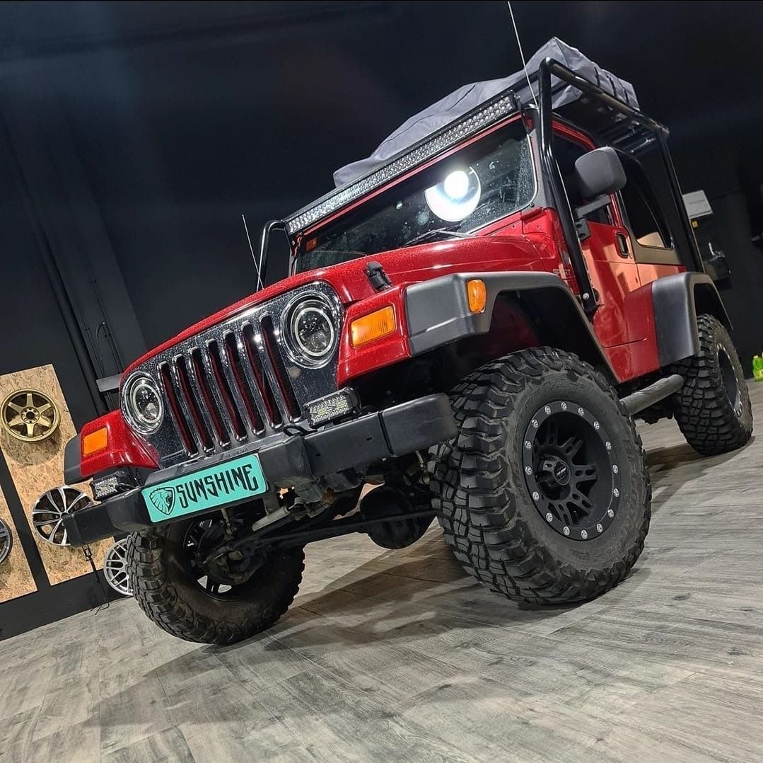 Un jeep rojo está estacionado sobre un piso de concreto en un garaje.