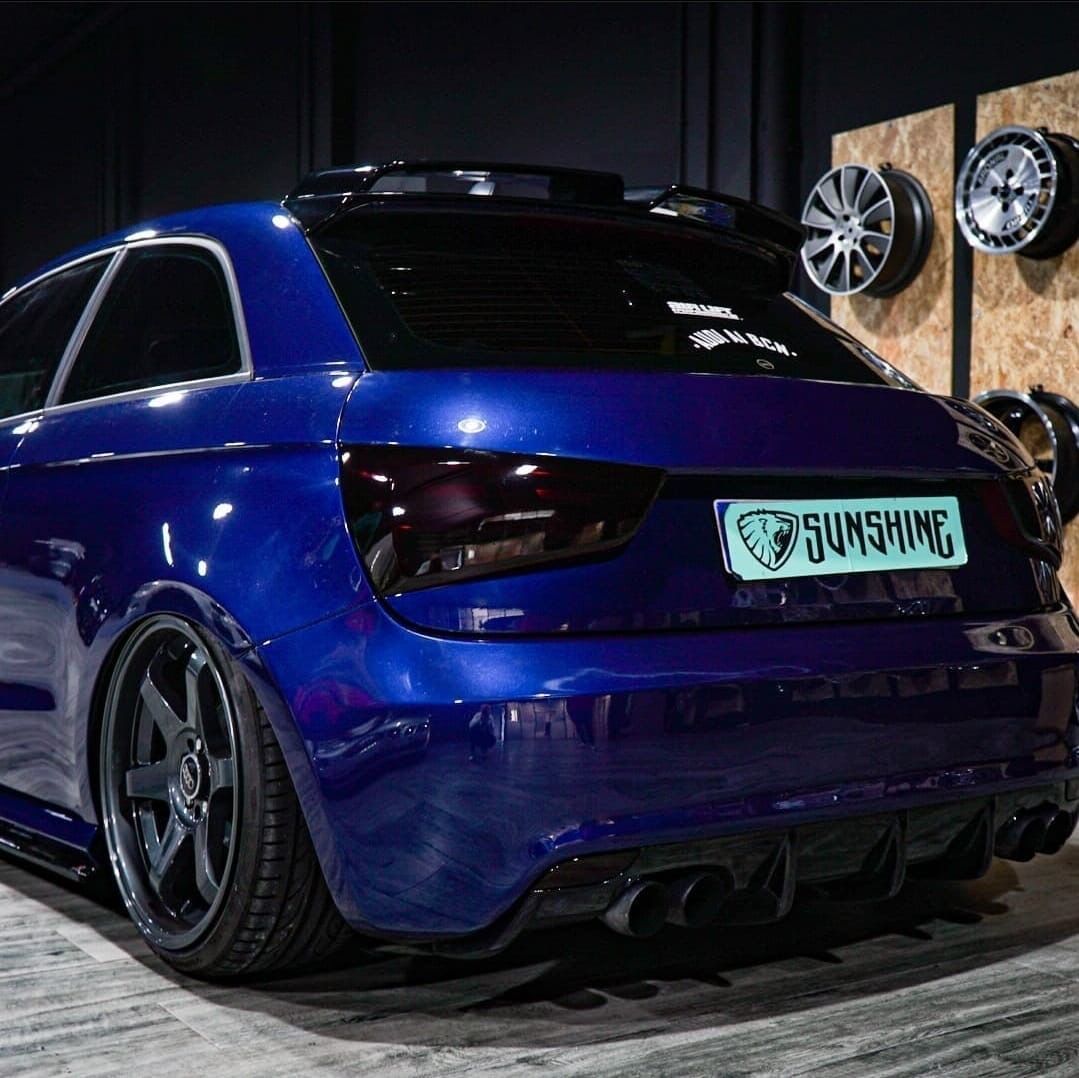 Un coche azul con matrícula que dice Sunshine está aparcado en un garaje.
