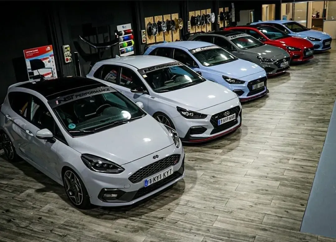 Un coche negro está aparcado delante de una pared de ruedas.
