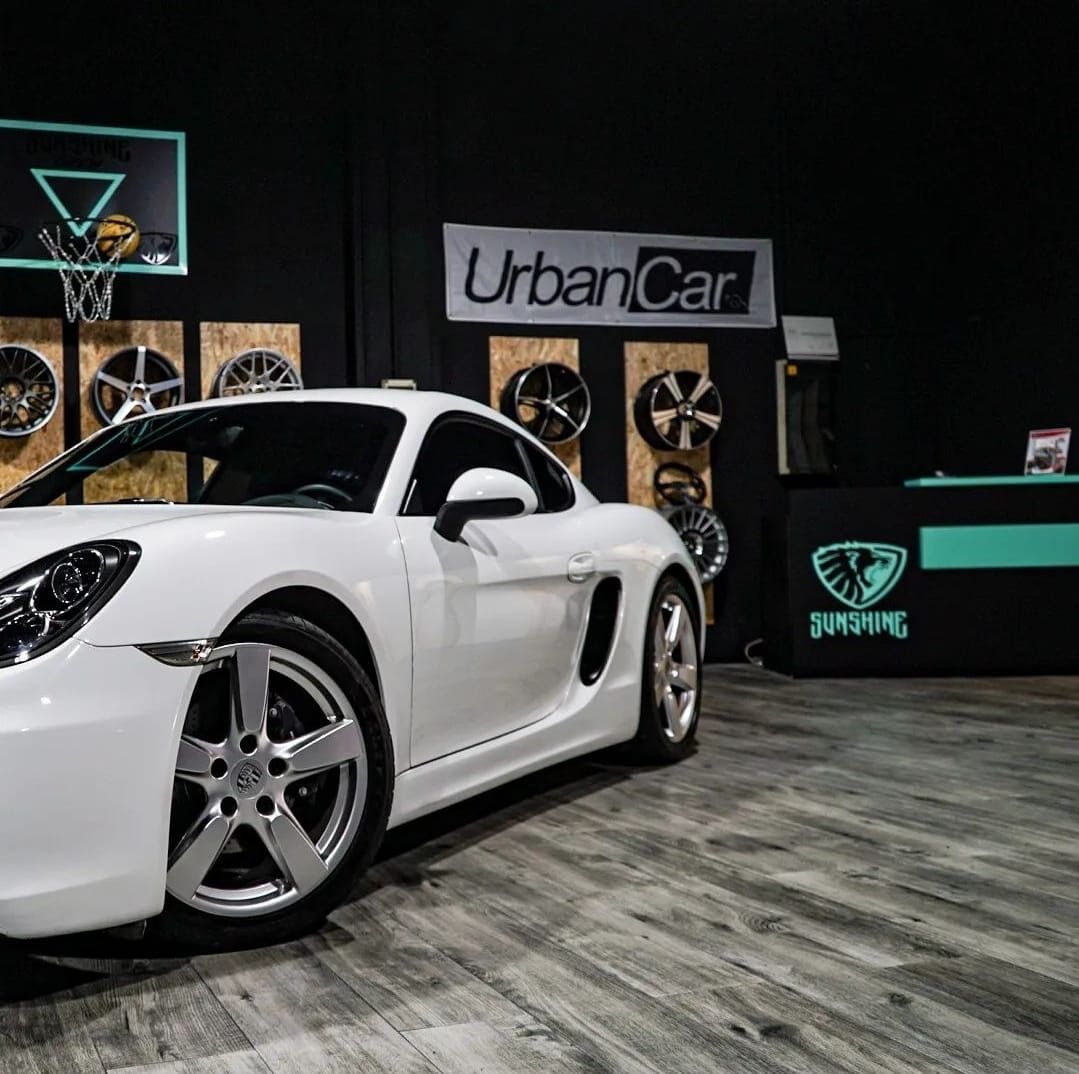 Un coche deportivo blanco está aparcado delante de un cartel que dice coche urbano.