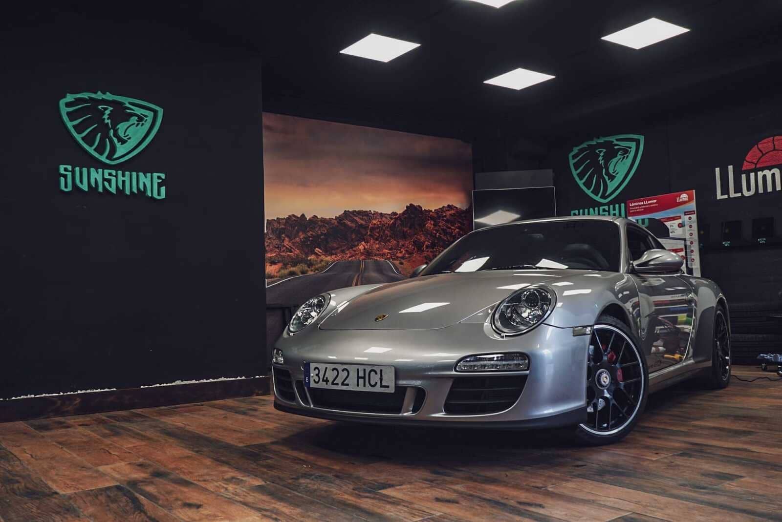 Un Porsche 911 GT3 plateado está estacionado en una sala de exposición.