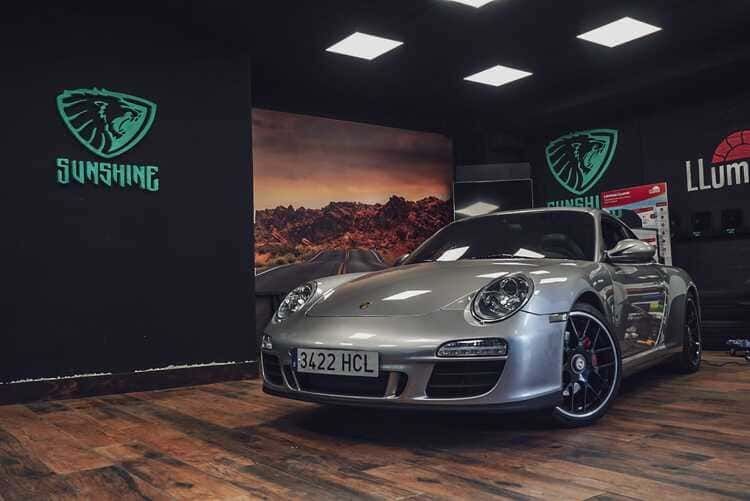 Un Porsche 911 plateado está aparcado en un garaje.