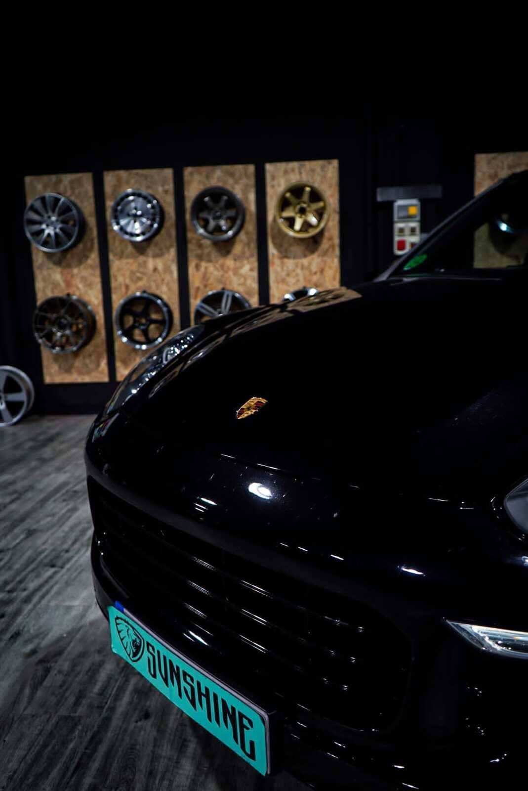 Un coche negro con matrícula que dice Sunshine está aparcado en un garaje.