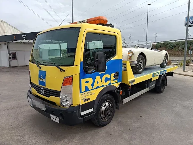 Automóvil blanco con importantes daños en la parte trasera, en una calle de la ciudad.