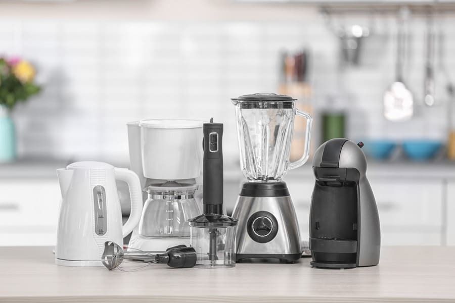 Una variedad de electrodomésticos de cocina se encuentran sobre un mostrador en una cocina.