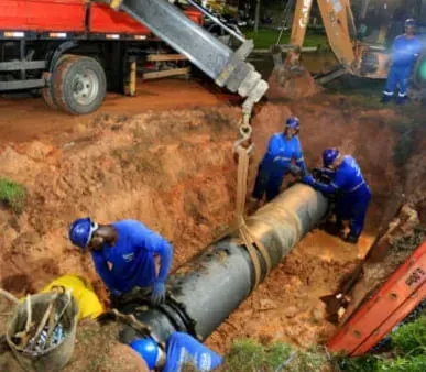 A group of men are working on a pipe in the dirt.