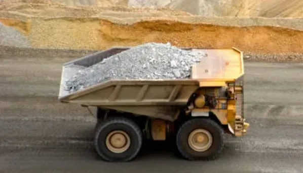 A dump truck is driving down a road filled with rocks.