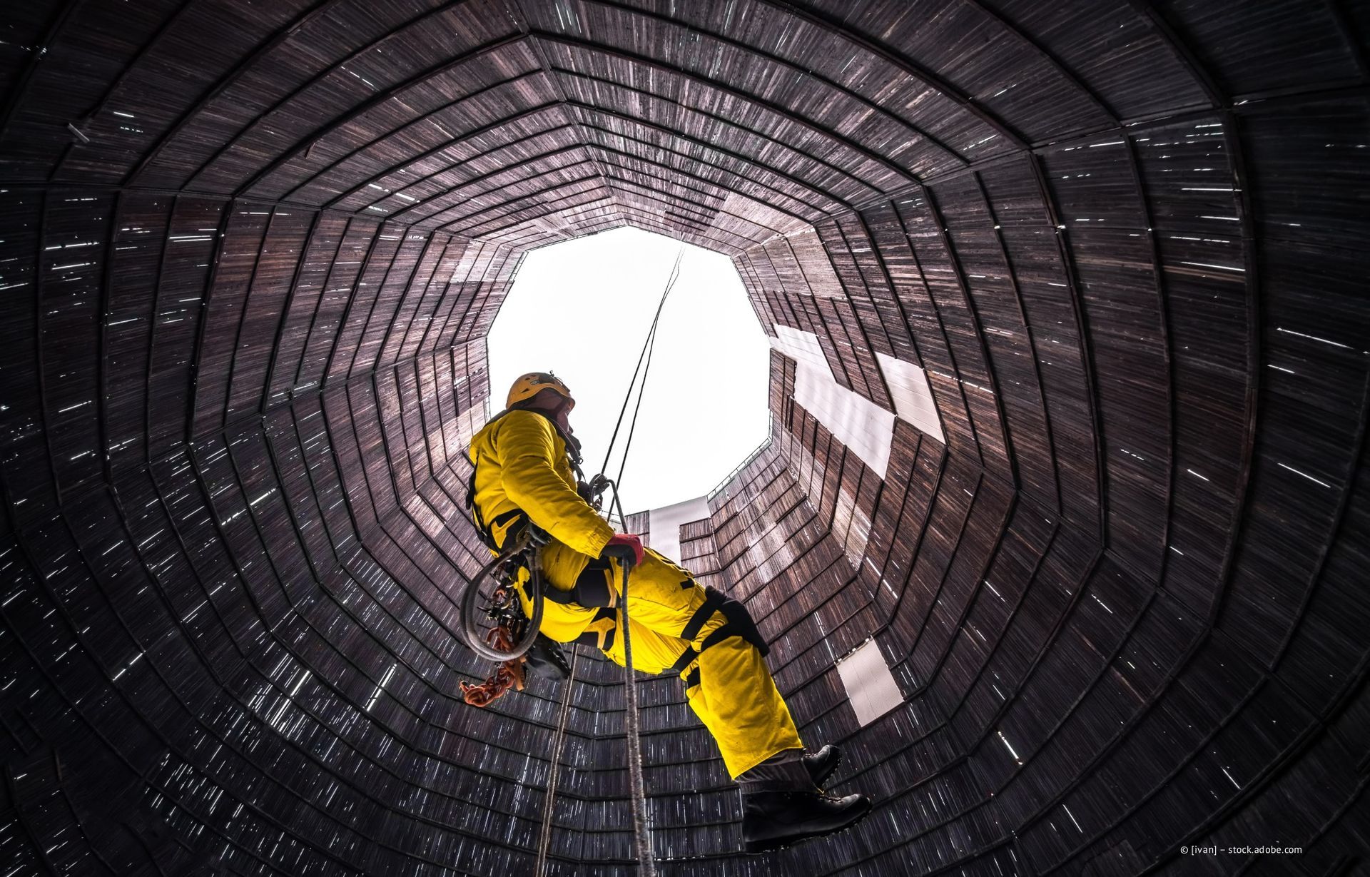 Fensterputzer an Seilen reinigen ein hohes blaues Glasgebäude. Zwei Arbeiter in Gurtzeug und Sicherheitsausrüstung.
