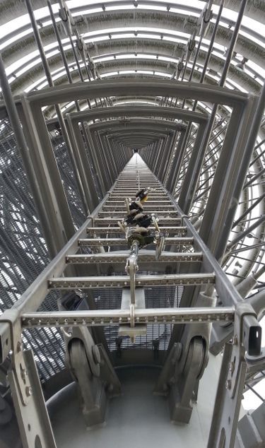 Arbeiter in Sicherheitsausrüstung seilt sich von einer Ölplattform ab. Im Hintergrund ist eine Offshore-Plattform zu sehen.