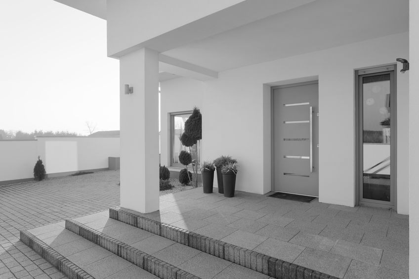 Una fotografía en blanco y negro de una casa moderna con escaleras y un porche.