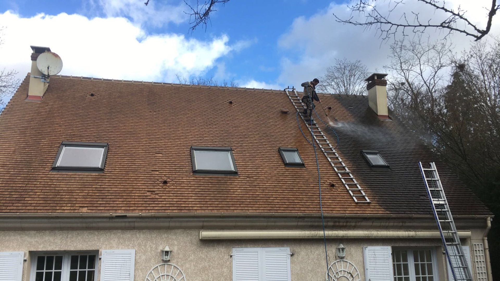 Un homme nettoie le toit d'une maison