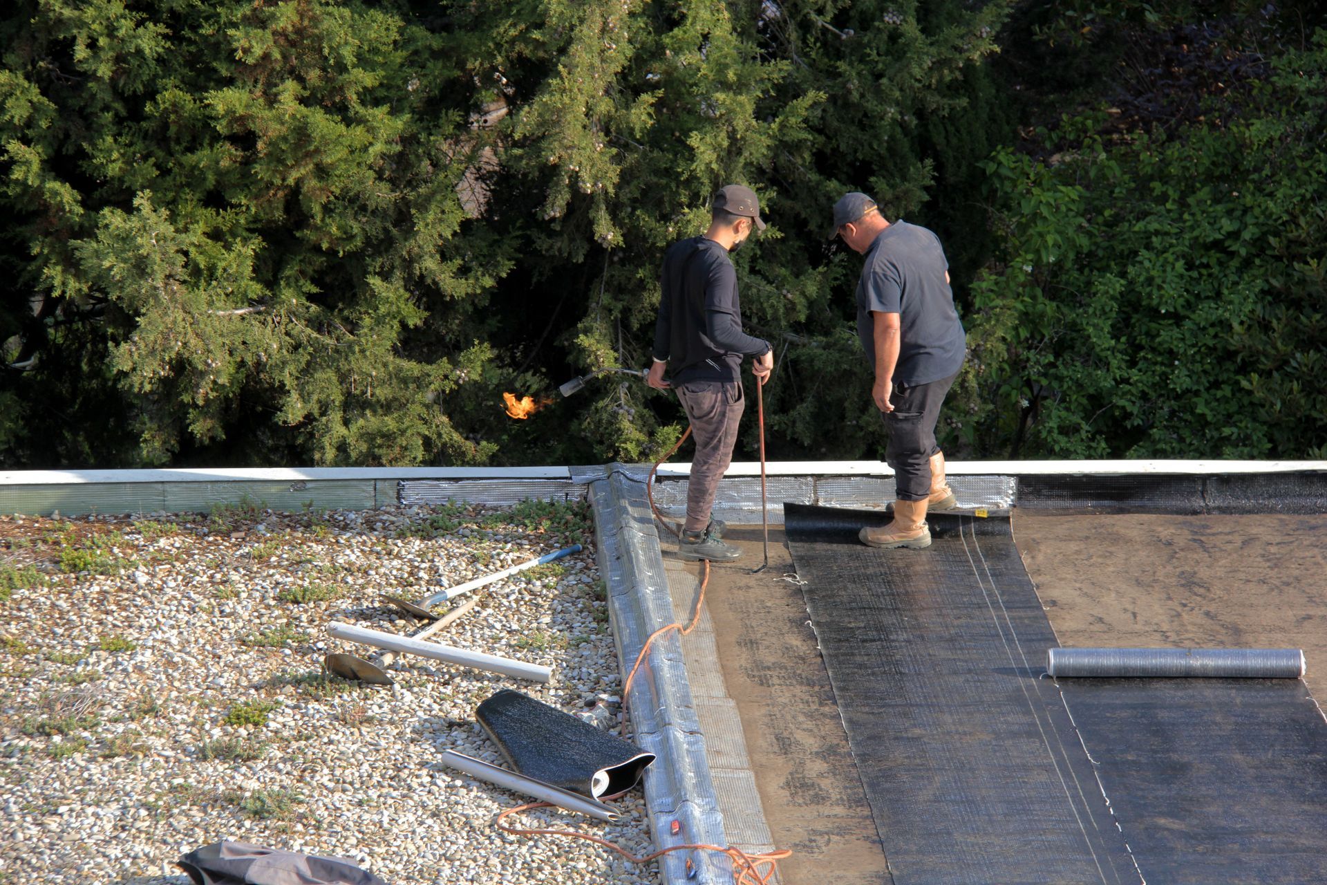 Deux artisans qualifiés posent l'étanchéité sur un toit