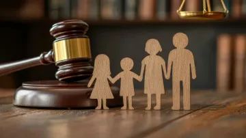 Figuras familiares de madera junto a un mazo y una balanza sobre una mesa de madera.
