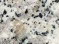 Nahaufnahme einer Arbeitsplatte aus weißem und grauem Granit mit schwarzen Sprenkeln.