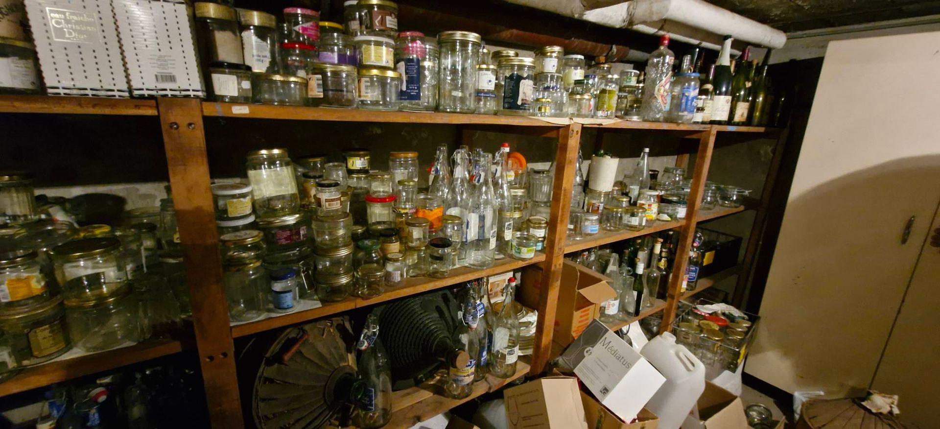Des étagères remplies de bocaux et de bouteilles dans un atelier encombré.