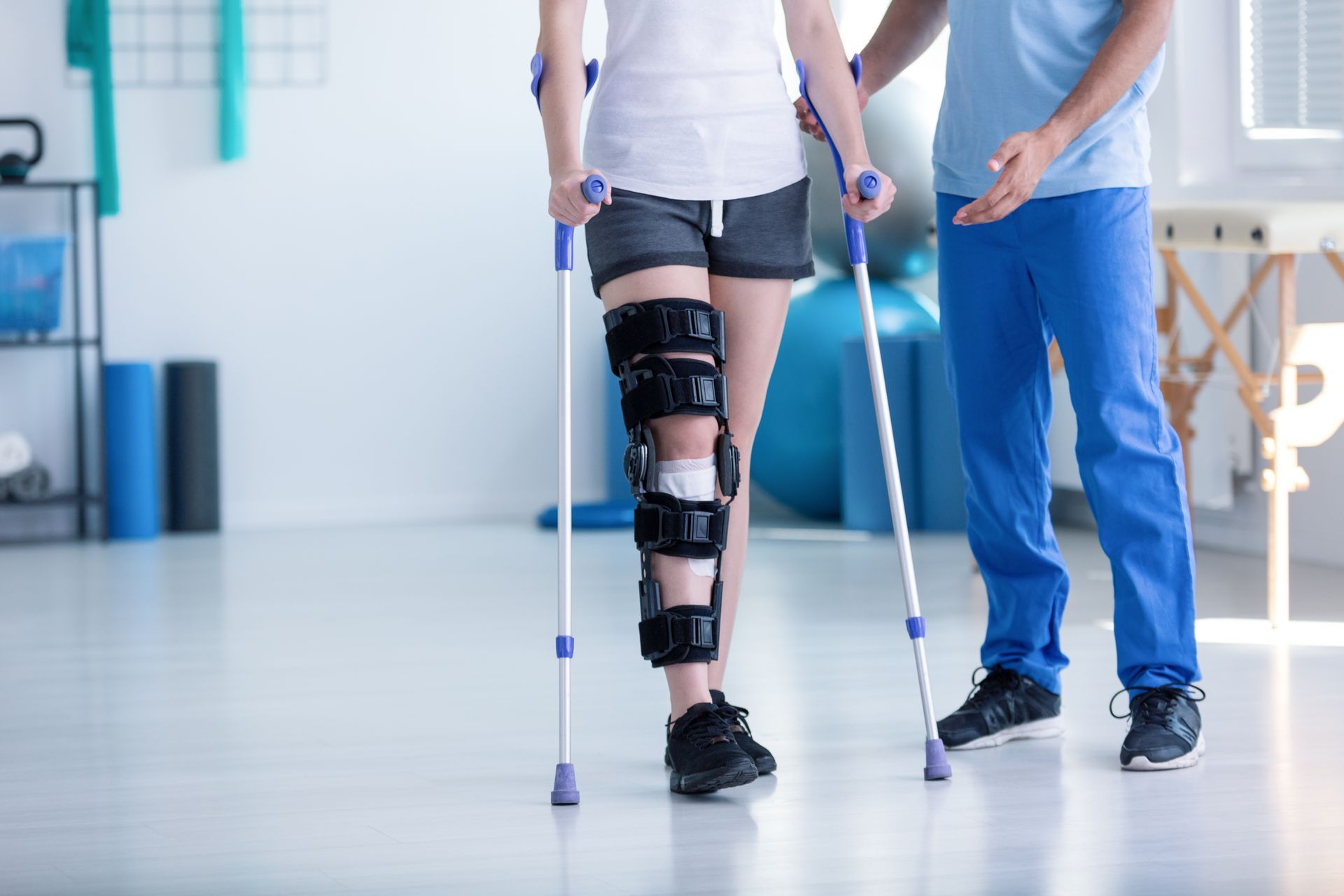 Une femme portant une attèle à la jambe et marchant avec des béquilles.