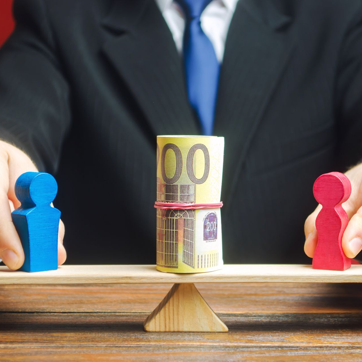 Un homme en costume fait tenir de l'argent en équilibre entre deux figures colorées sur une balance.