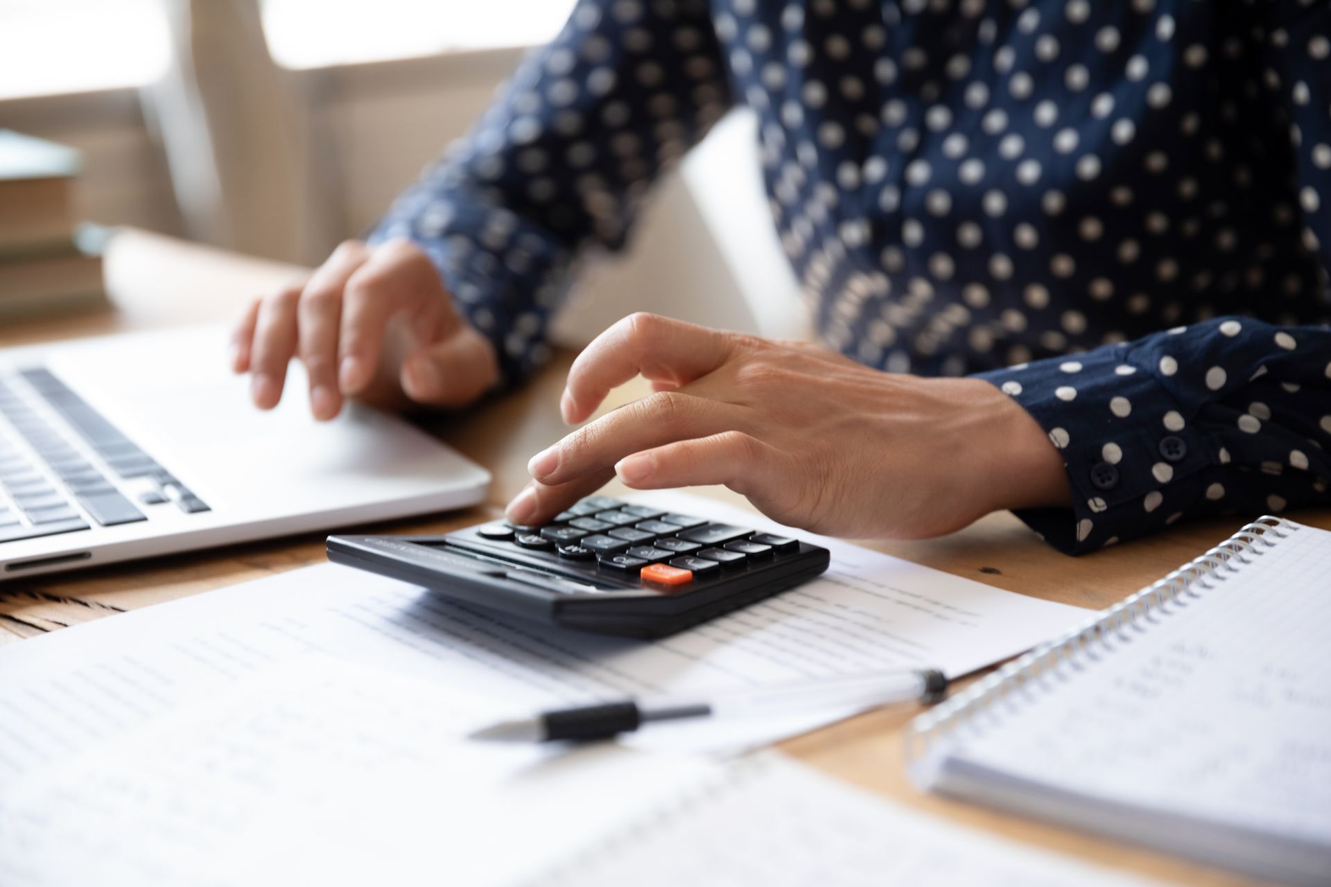 Femme consultant un ordinateur et effectuant des calculs.