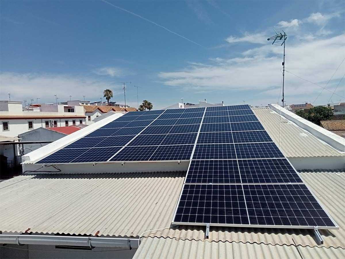 Paneles solares instalados en un techo de metal corrugado bajo un cielo parcialmente nublado.