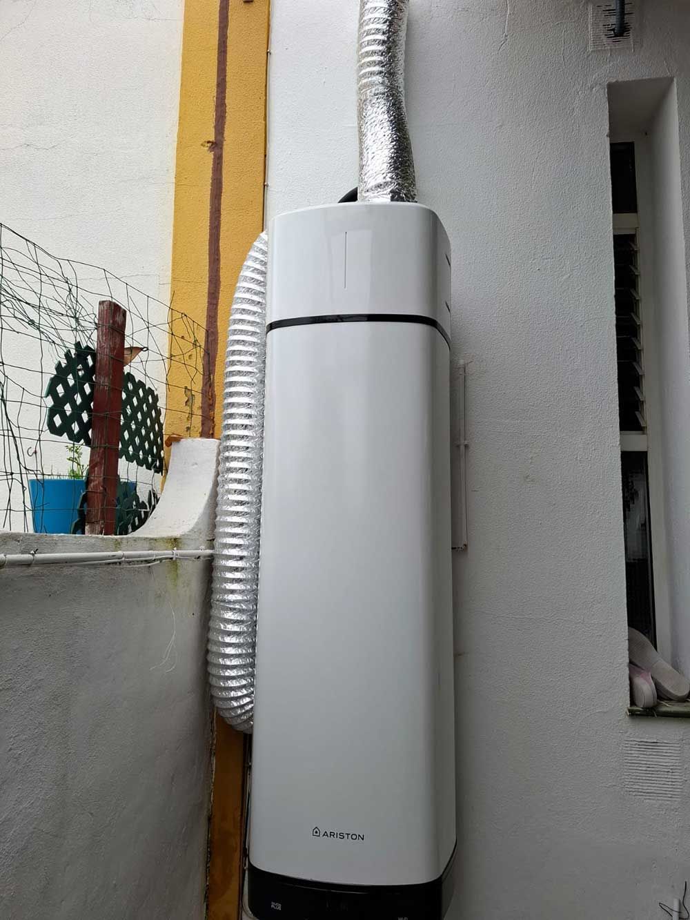 Calentador de agua de pared de color blanco con tubo de escape plateado.