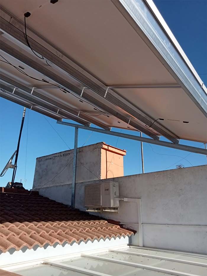 Paneles solares instalados en un tejado, con un cielo azul claro de fondo.