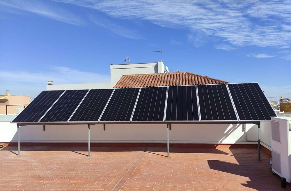 Paneles solares en un tejado plano contra un cielo azul.