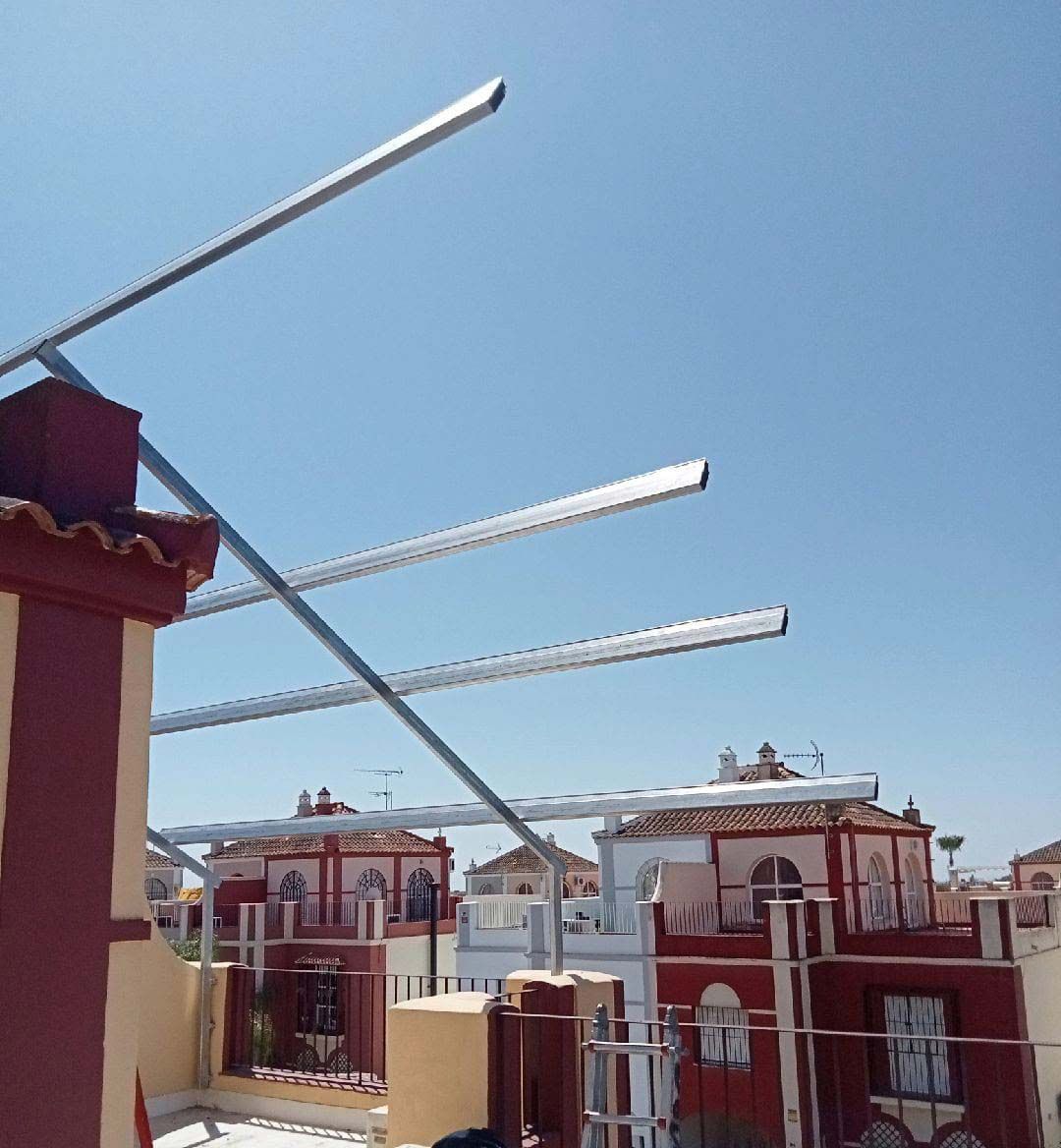 Instalación de una estructura metálica en un tejado. Edificios al fondo y cielo azul.